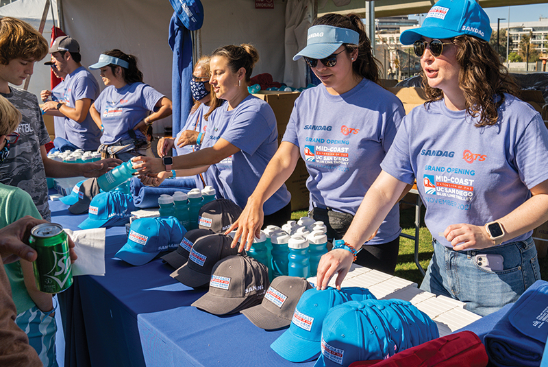 Event volunteers hand out giveaways at the Mid-Coast Trolley Grand Opening Celebration